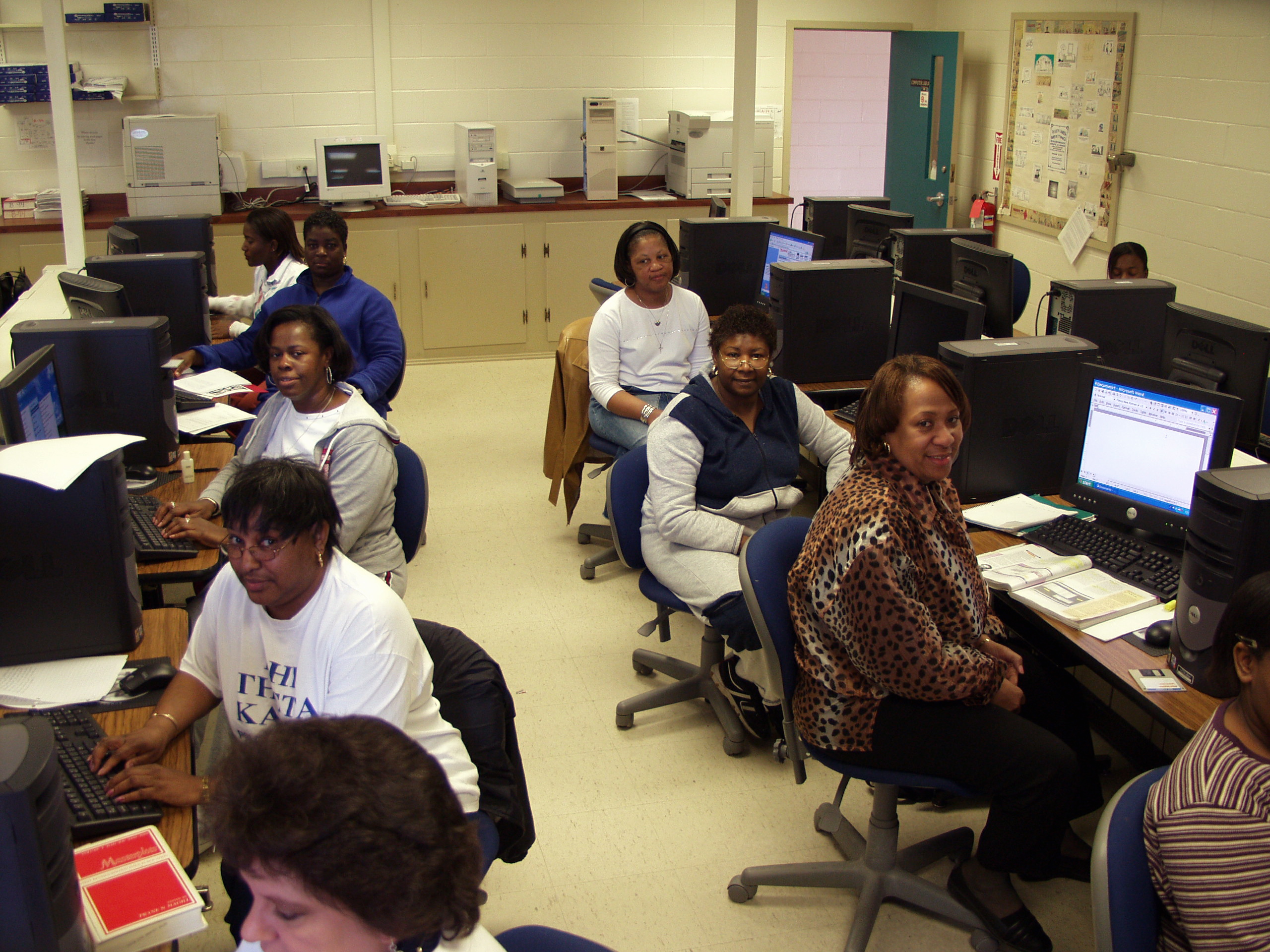 A group of women seated in a room with rows of computers on tables